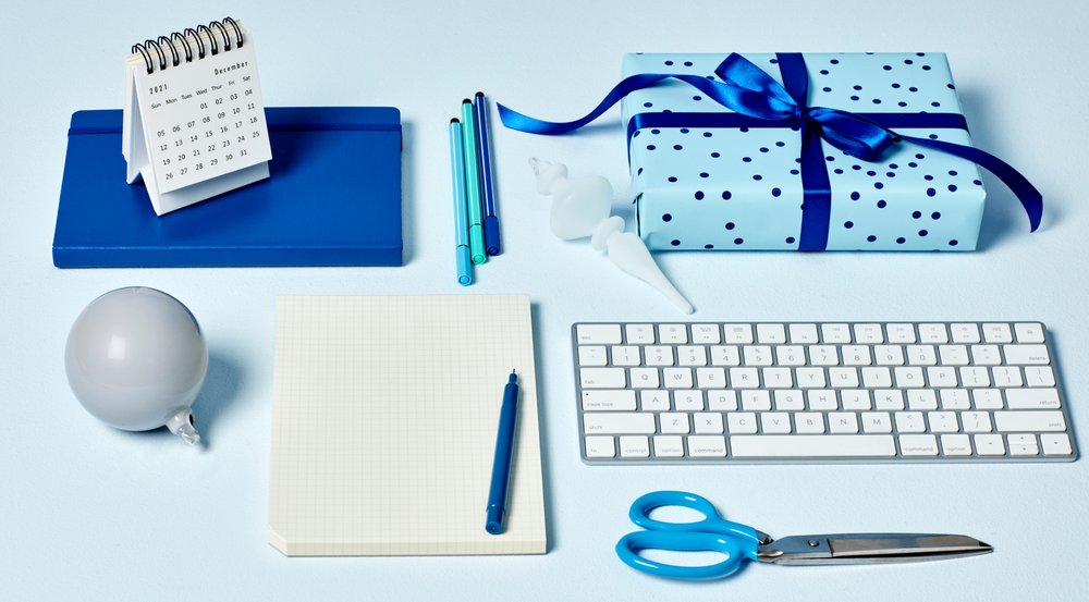 Petit calendrier, carnets, stylos, paire de ciseaux, boule de Noël, boîte cadeau et clavier sur un bureau